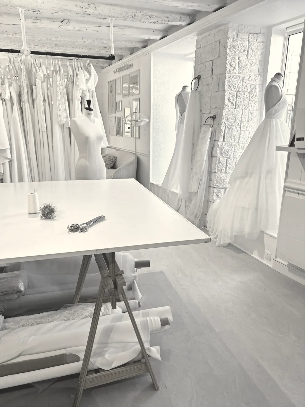 Atelier Lolette à Gap : table de coupe sur tréteaux, rouleaux de tissu et robes de mariée en cours sur mannequins