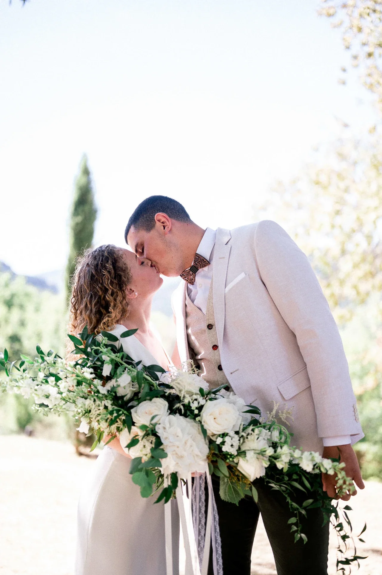 Baiser des mariés, la mariée tenant un grand bouquet blanc et vert