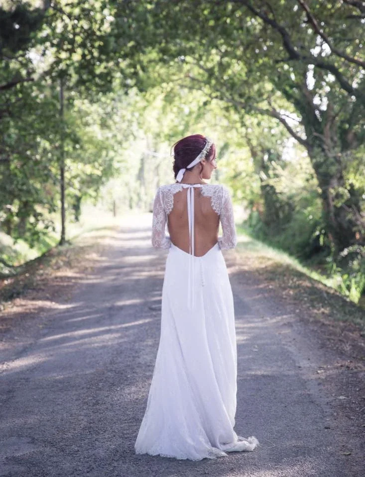 Mariée de dos sur un chemin arboré, dos nu bordé de dentelle