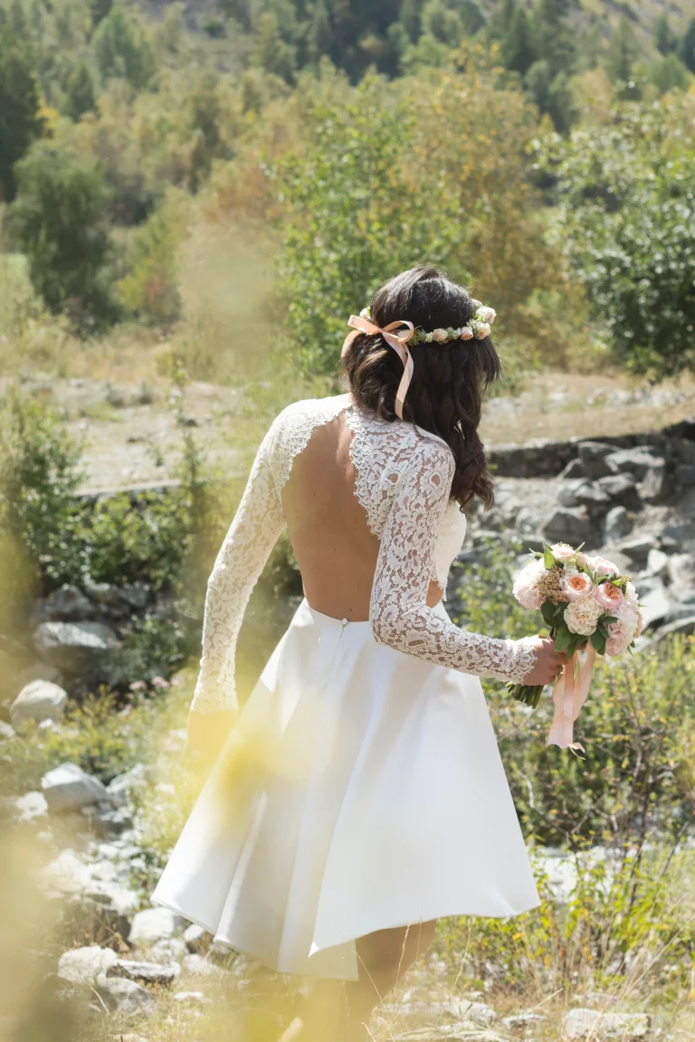 Mariée en robe courte à dos nu et manches en dentelle, couronne de fleurs