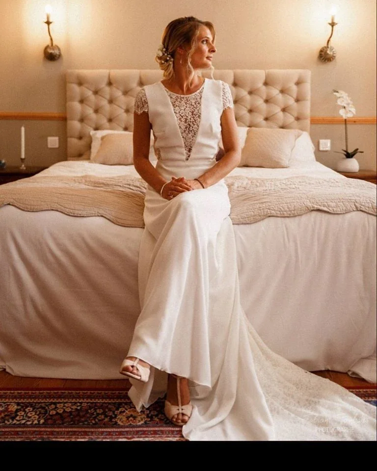 Mariée assise au bord d'un lit, robe à empiècement en dentelle
