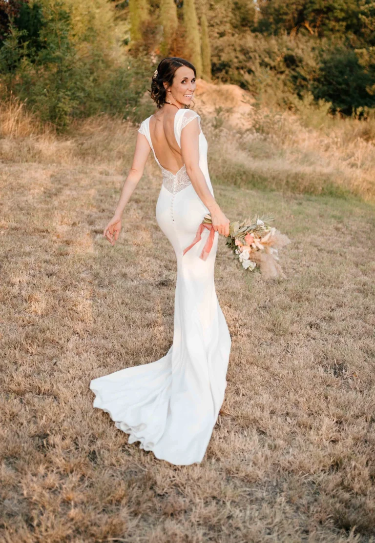 Mariée de dos en robe sirène à dos en dentelle, champ doré