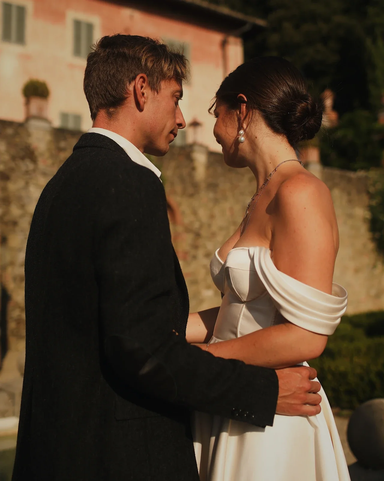 Couple face à face devant une villa toscane, robe sur mesure en satin de soie