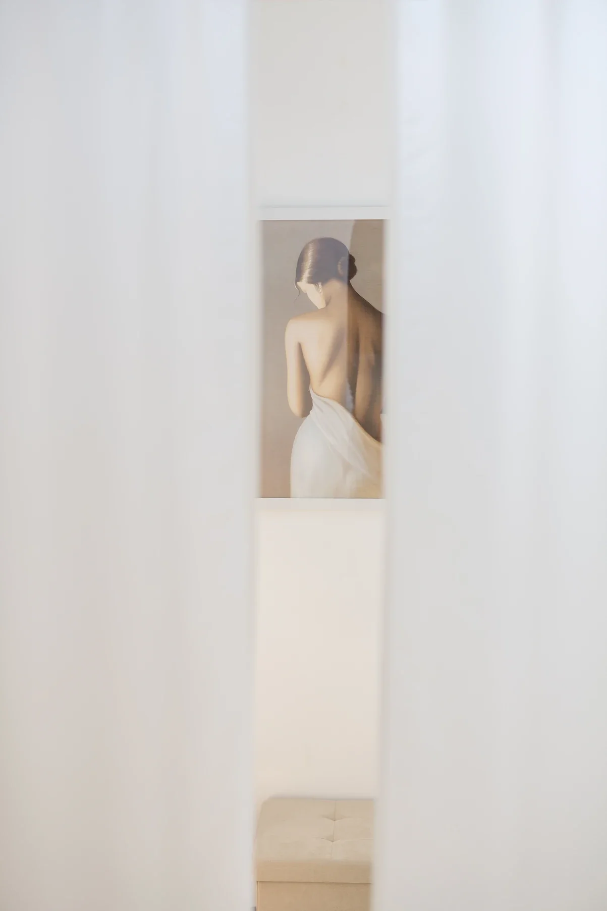 Showroom Lolette à Gap : cabine d'essayage aux voilages blancs entrouverts, tableau et pouf beige