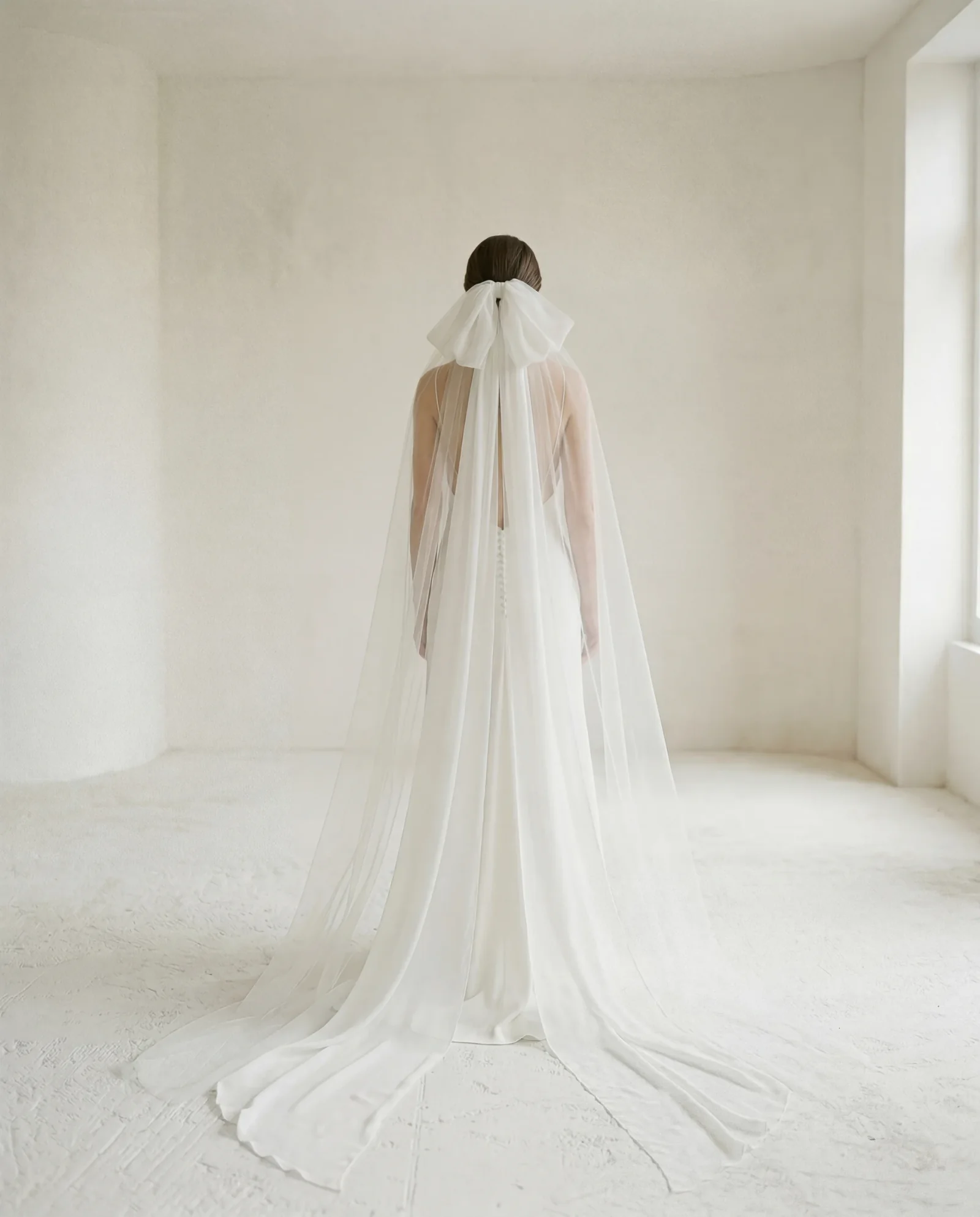 Mariée de dos portant un long voile noué dans les cheveux, collection La Septième